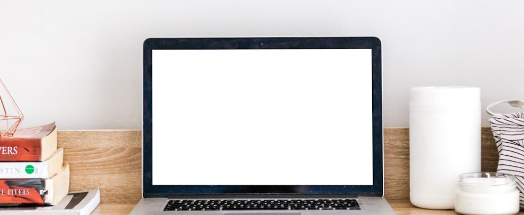 a clean workspace with a blank laptop screen and a few books on a desk