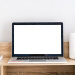 a clean workspace with a blank laptop screen and a few books on a desk