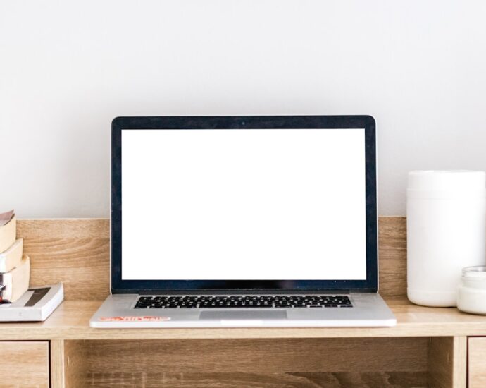 a clean workspace with a blank laptop screen and a few books on a desk